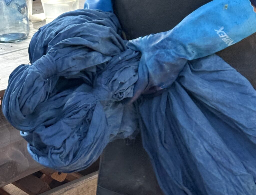 Hands working with textiles in an indigo dye studio